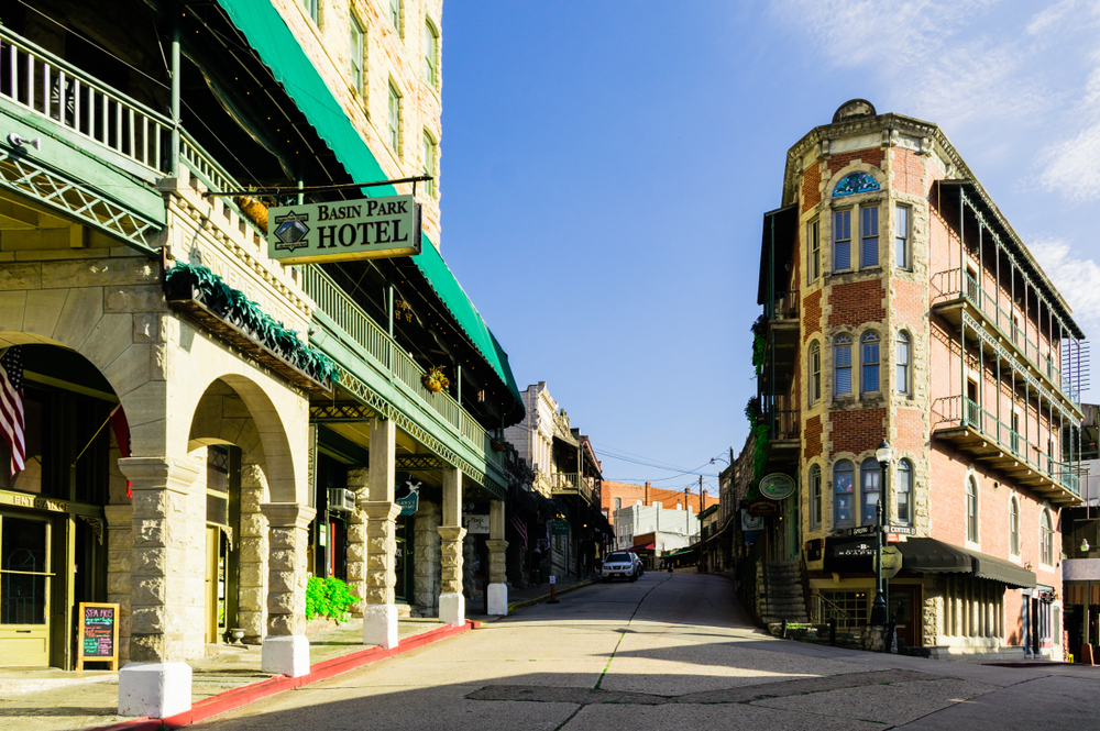 The Eureka Springs downtown lined with buildings and a sign for a hotel with a blue sky and is one of the best Arkansas attractions.