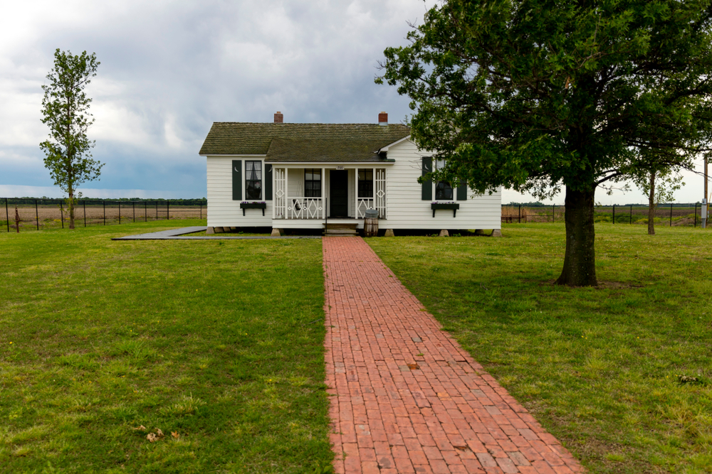 white and black home of Johnny Cash in Arkansas with green grass and red path surrounded by trees