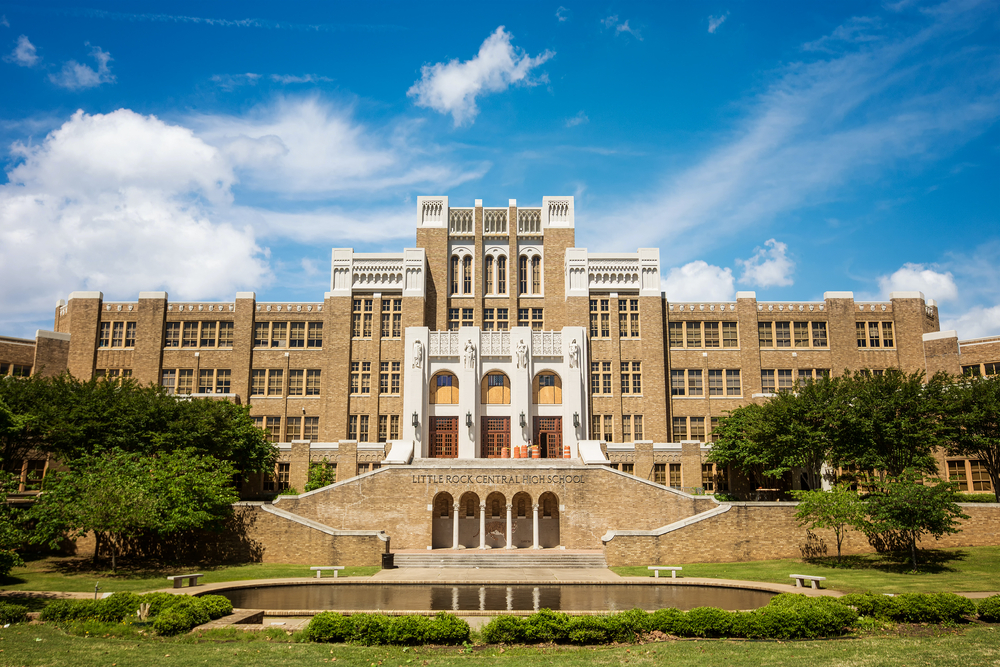 brown building that is Little Rock Central High School with blue sky and white clouds that is an important historic site in Arkansas.