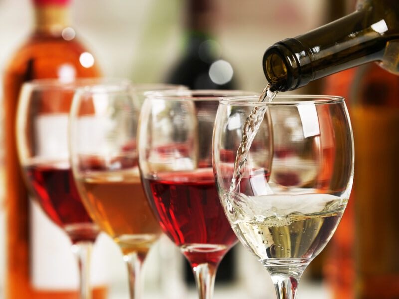 A close up of wine being poured into a series of wine glasses. 