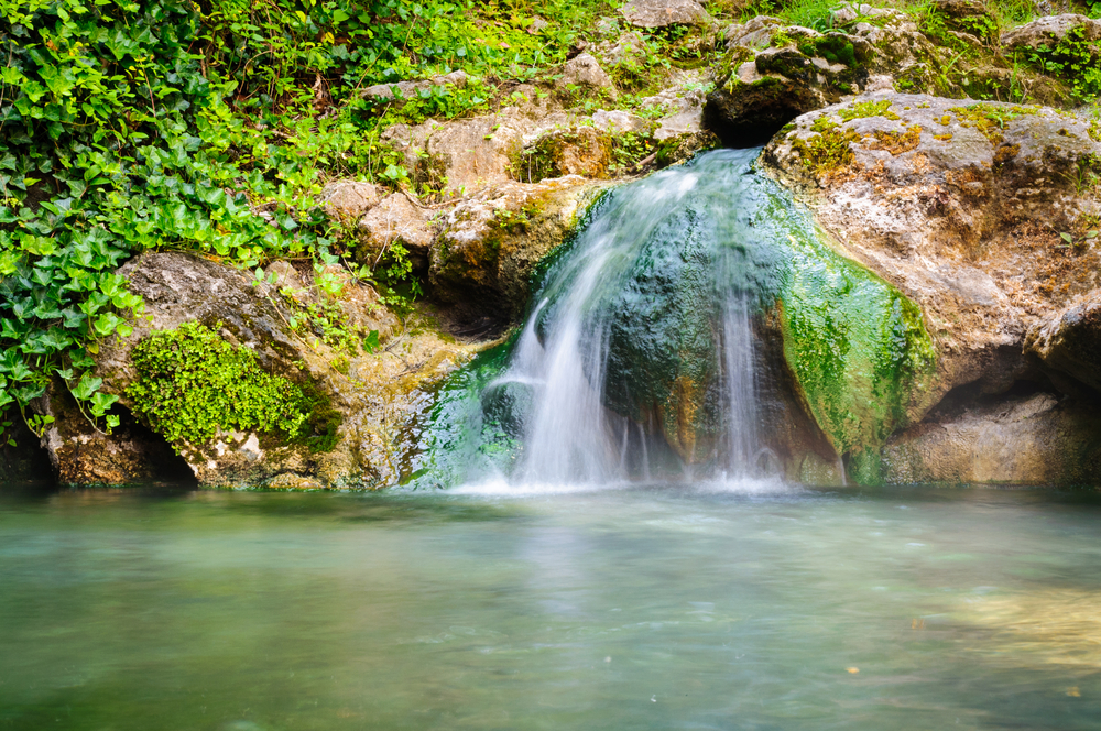 Small waterfall at Hot Springs National Park. with greenery and rocks throughout. 