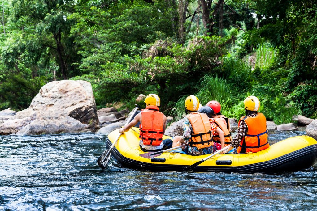 Photo of people white water rafting in a yellow rafting boat.
