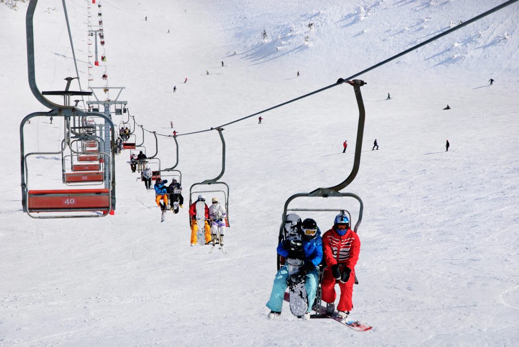 Photo of several people riding a ski lift. 