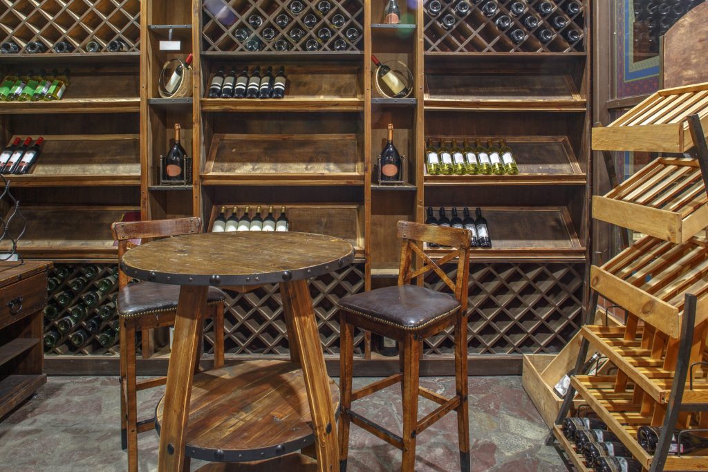 Photo of the inside of a wine tasting room featuring wine bottle of wooden racks. 