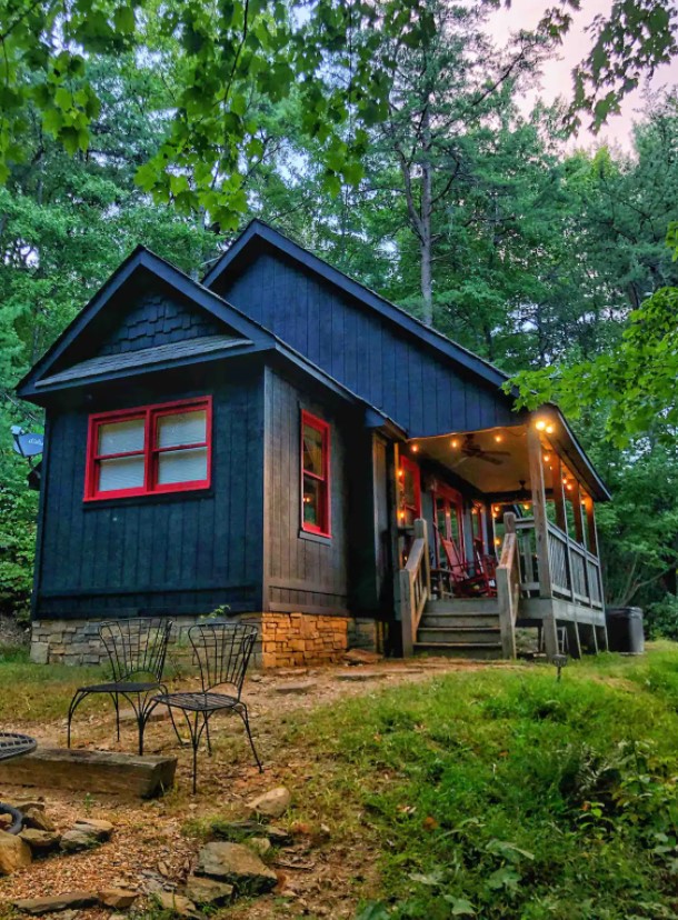 A black cabin with red trim surrounded by woods in Georgia