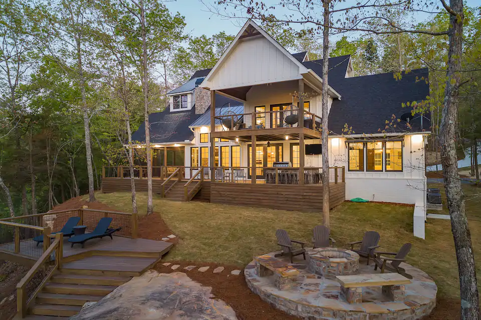 view of the firepit, sun deck, and screened in porch, and forest surroundings of the Lake House at Emerald Cove. 