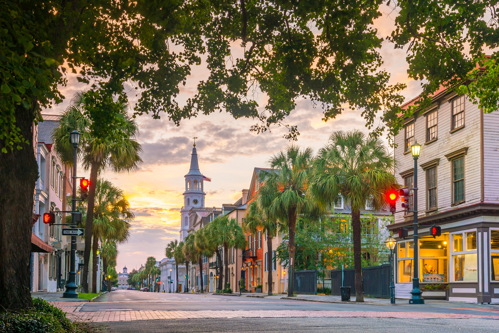 A street in Historic Charleston with palmetto trees and charming buildings at sunset one of the best south carolina road trips