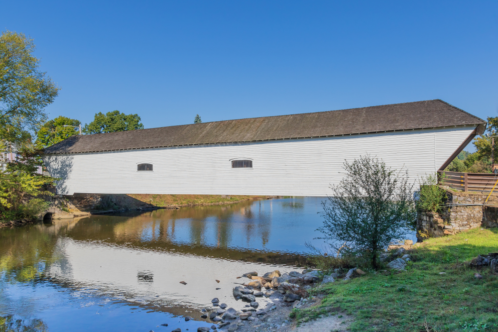 A white covered bridge in Tennessee that crosses a wide creek