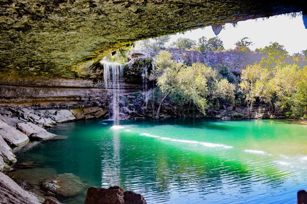 The limestone waterfall trickles above from Hamilton Pool, one of the best hidden gems in Texas.