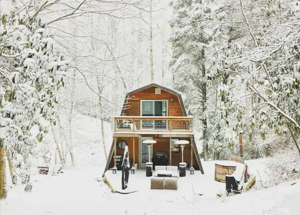 A charming cabin in the snow surrounded by woods in North Carolina one of the coziest cabins in the South