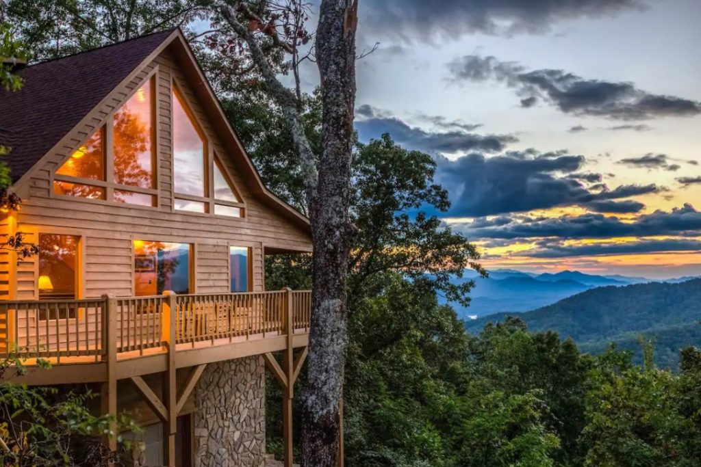 The front of a cabin set against a mountain side with views of the Great Smoky Mountains next to it