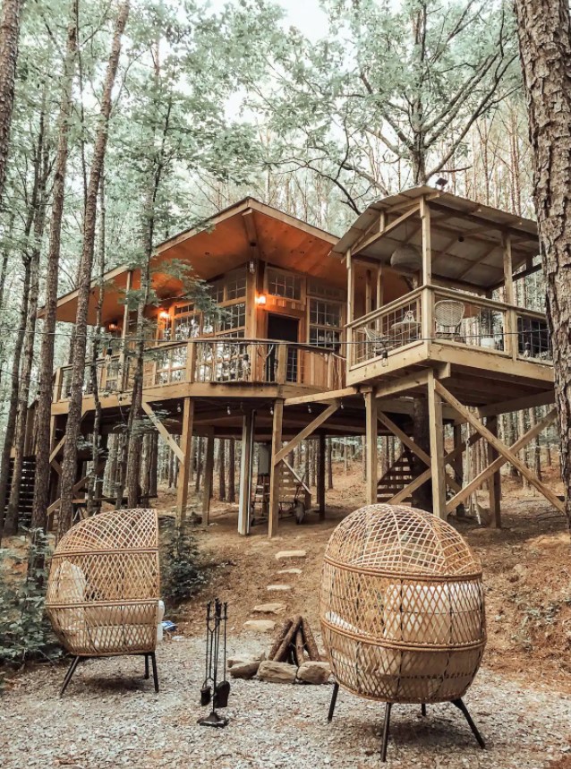 Looking up at a cabin from the firepit surrounded by trees in Alabama