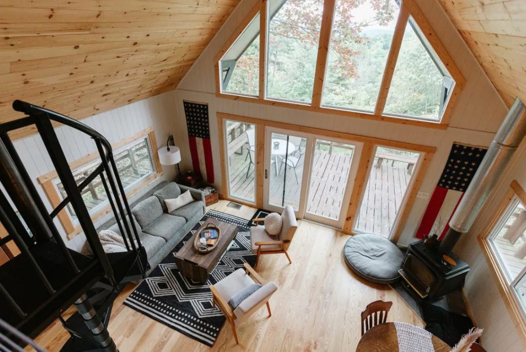 The view looking down from the loft of a cozy cabin in the South with large windows and a front porch