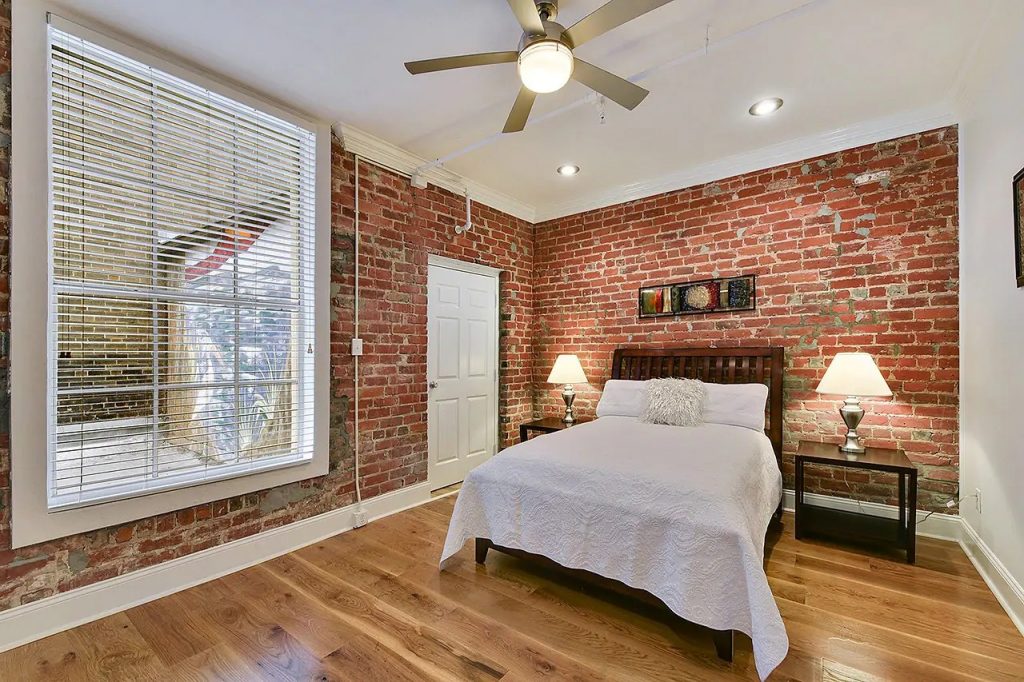 Photo of a condo on Union Street that is an Airbnb in New Orleans. Beautiful bedroom with historic brick wall.