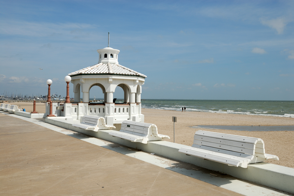 A photo of white benches on Corpus Christi Beach. One of the prettiest beaches in Texas.