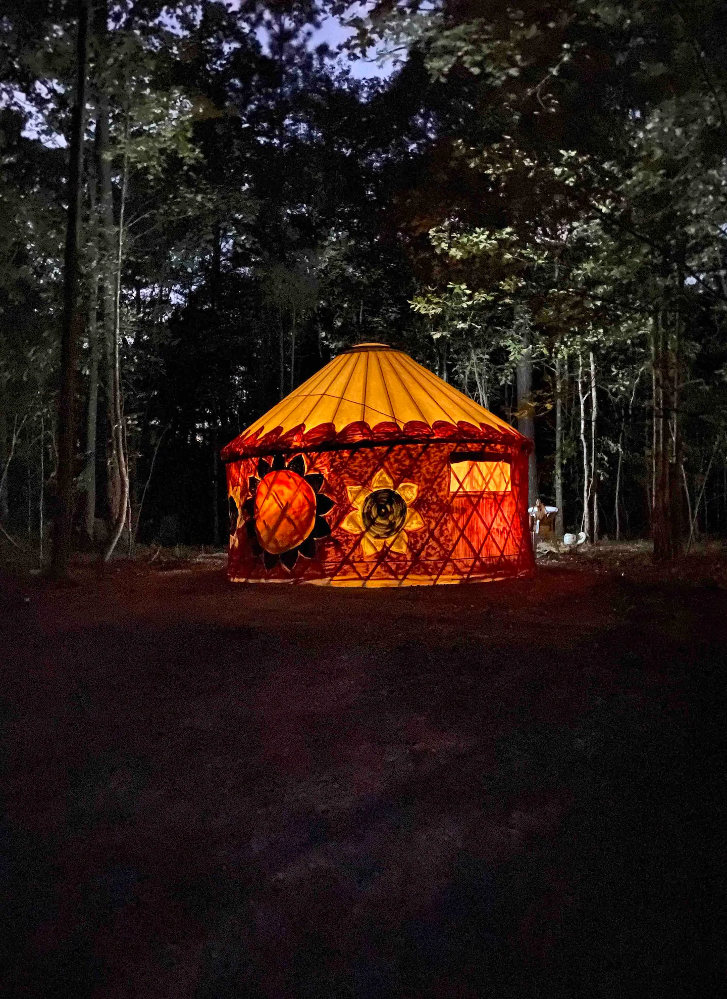 Photo of a hand-painted yurt Airbnb being illuminated from the inside. 