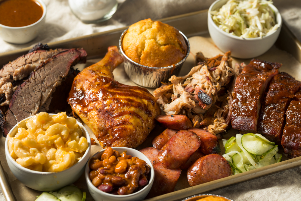 Photo of a BBQ platter of ribs, sausage, smoked chicken, and brisket.