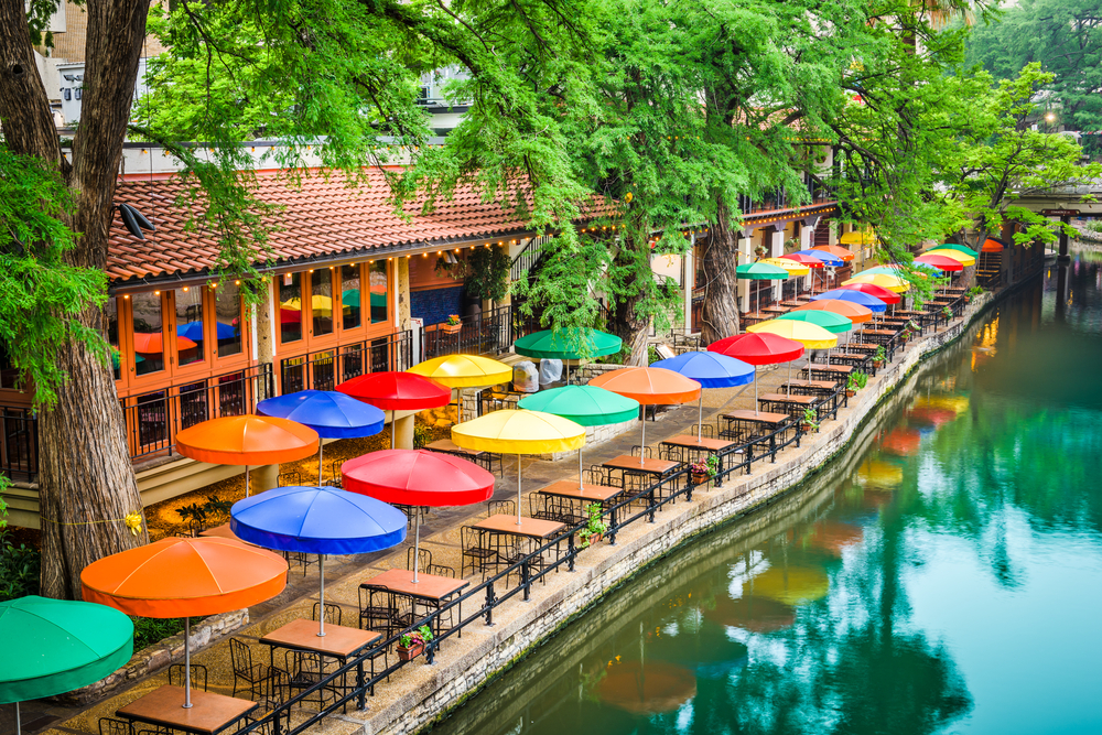 Photo of colorful umbrellas on a restaurant patio lining the river walk in San Antonio, one of the best weekend getaways in Texas.