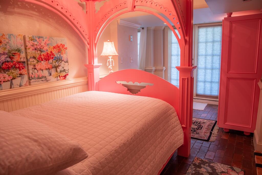 A beautiful pink bedroom with a pink bed and a large window.