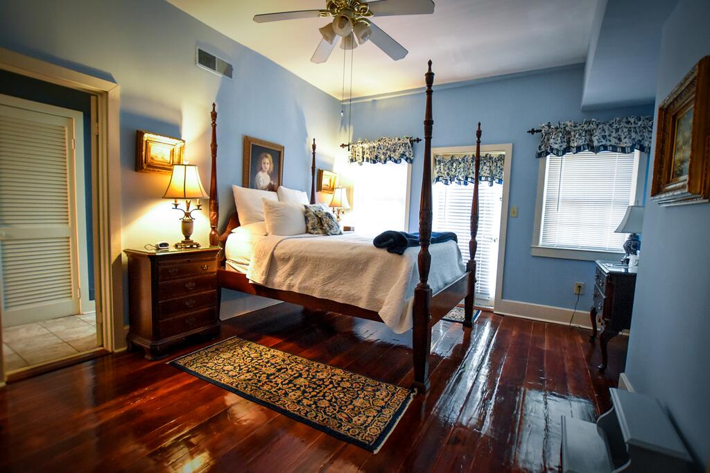 A four poster bed in a blue bedroom with a wooden floor in an article about bed and breakfast in savannah