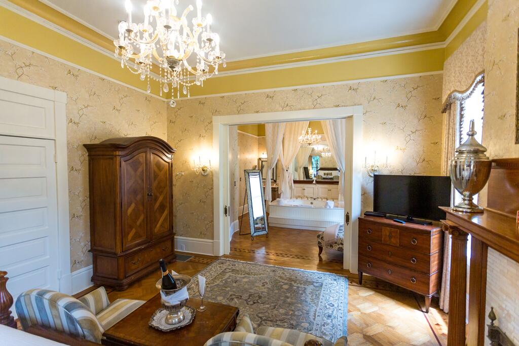 A yellow room with wooden furniture and a crystal chandelier in a bed and breakfast in savannah