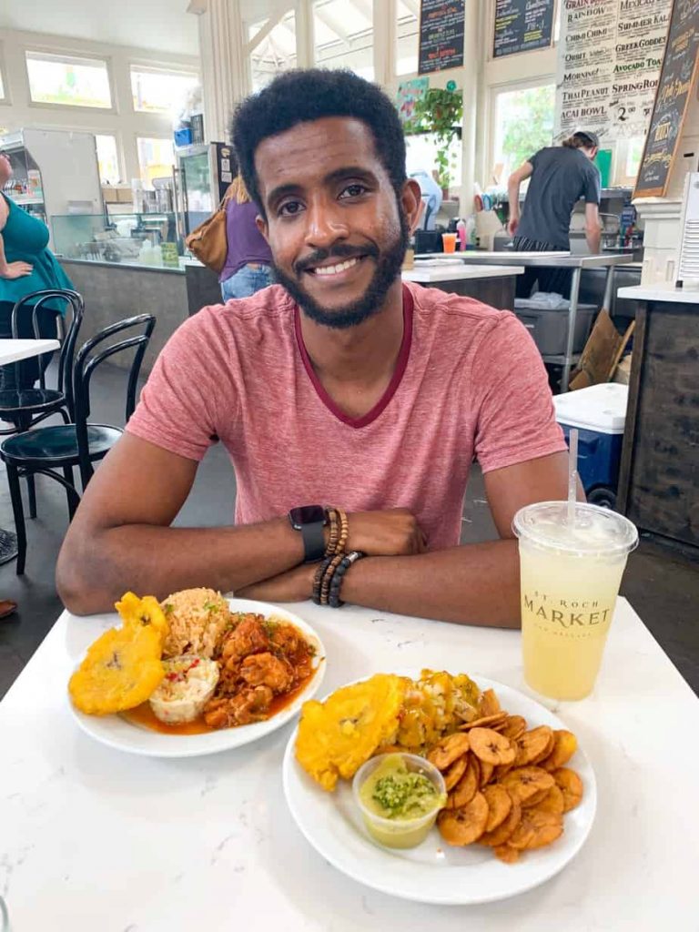 A man sitting at a table with two large plates of food at it in New Orleans