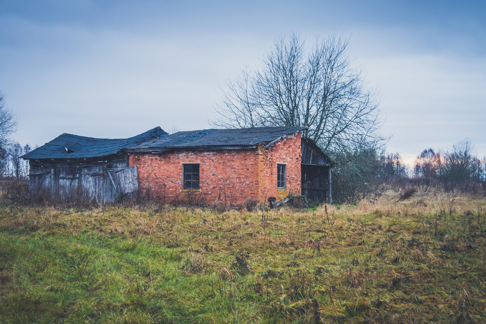 Photo of an abandoned brick home in the middle of an empty field in Alabama