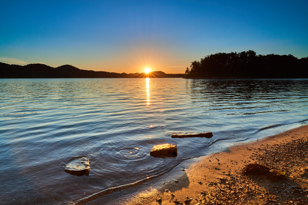 A photo of the sun setting on the horizon of a Kentucky beach.