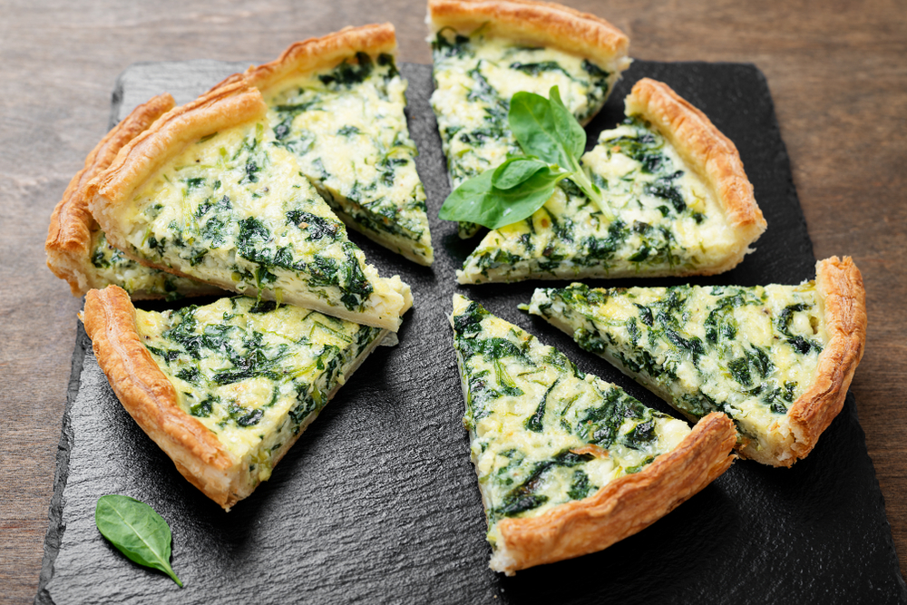 A plate of spinach quiche on a black slab