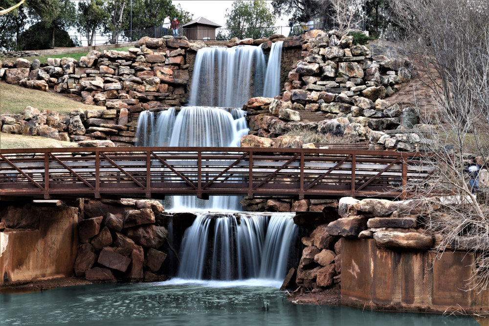 Wichita Falls a three layered waterfall surrounded by rocks with a bridge in front one of the best waterfalls in texas