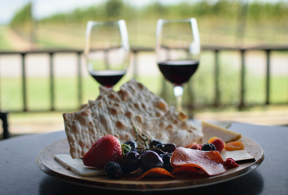 two glasses of red wine and cheese and meat on a table in an article about wineries of the south