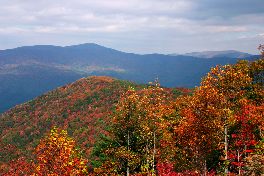 Photo from Fort Mountain where you can see a mountain range covered in bright hues of orange, green, and red. 