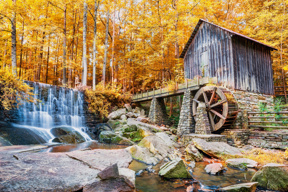 Photo of an old mill near Marietta standing beside a small cascading waterfall during Fall in Georgia. 