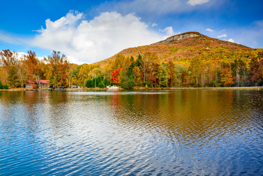 Photo looking across a lake where you can see Yonah Mountain covered in Georgia fall foliage of deep oranges and reds. 