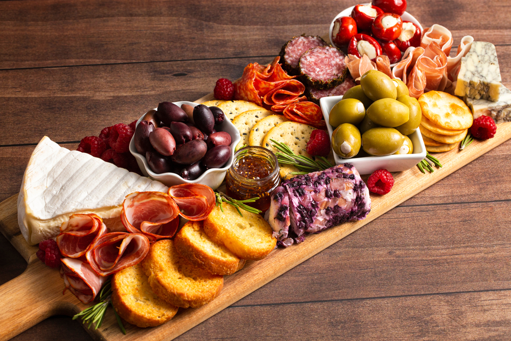 A charcuterie board loaded with cheeses, olives, meats, crackers, and crostini. Restaurants in San Antonio like Bliss offer such delights