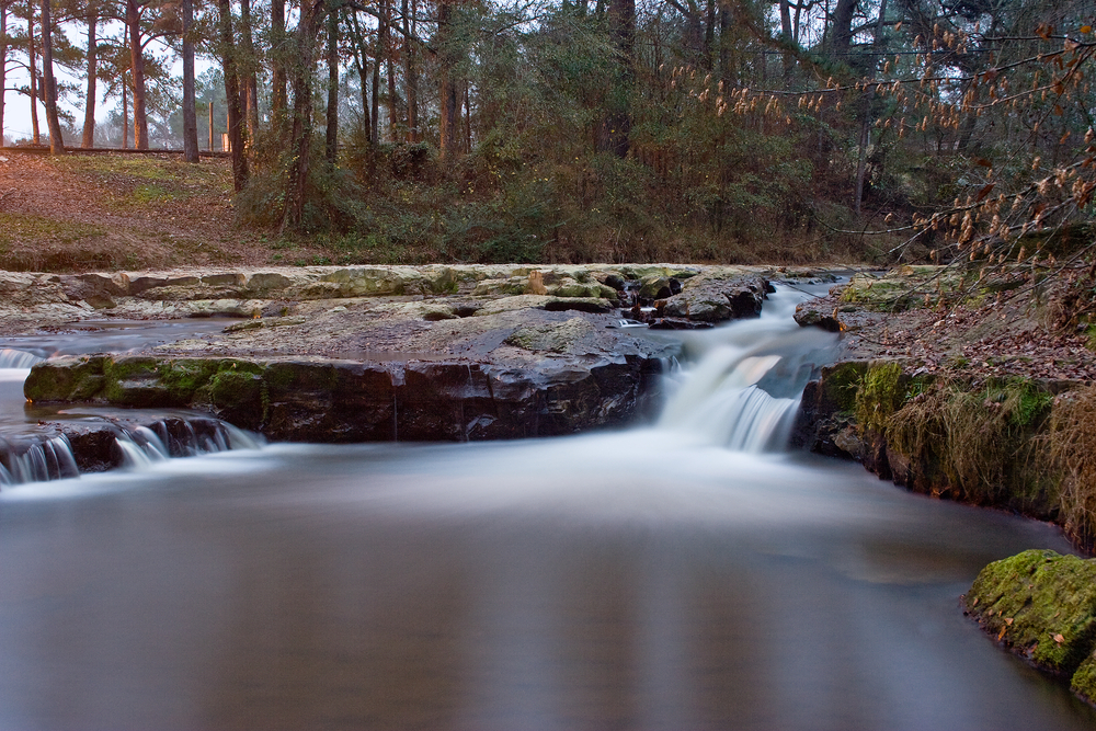 Dusk at a rushing waterfall in Mississippi surrounded by forest.