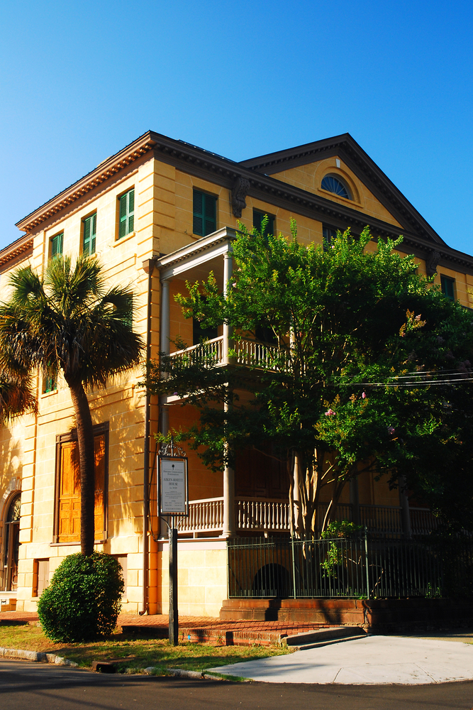 Exterior of the yellow Aiken-Rhett House next to trees.