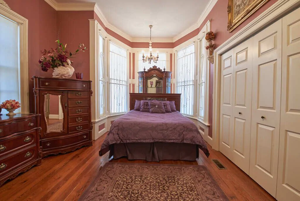 Photo o  a bedroom with antique furniture at the 1876 Victorian Mansion, one of the best VRBO in Savannah