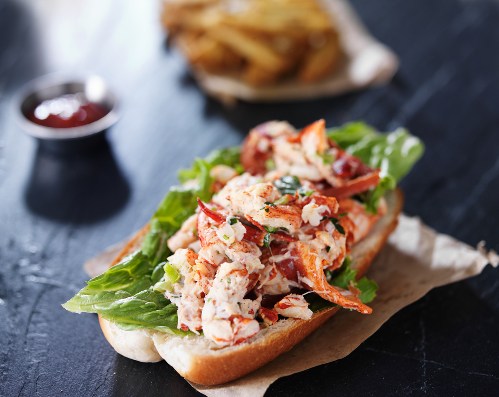 lobster roll on a parchment paper laying on a black counter