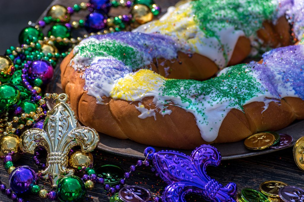 A King cake is topped with green, yellow, and purple sprinkles, the signature colors of Mardi Gras