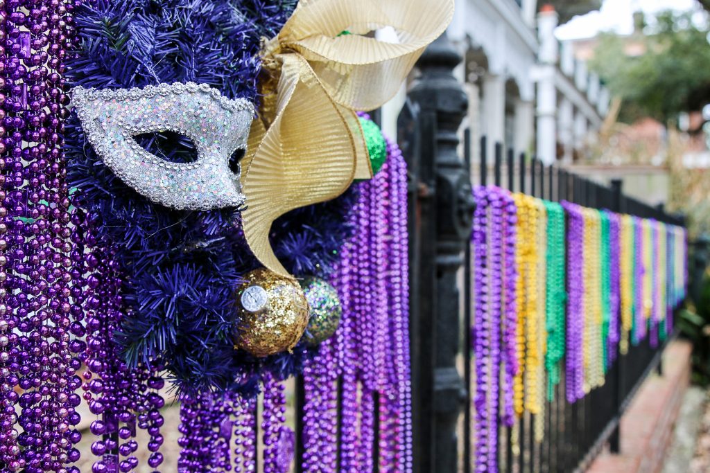 Beads hang from a fence along with masks during Mardi Gras, the best time to visit New Orleans