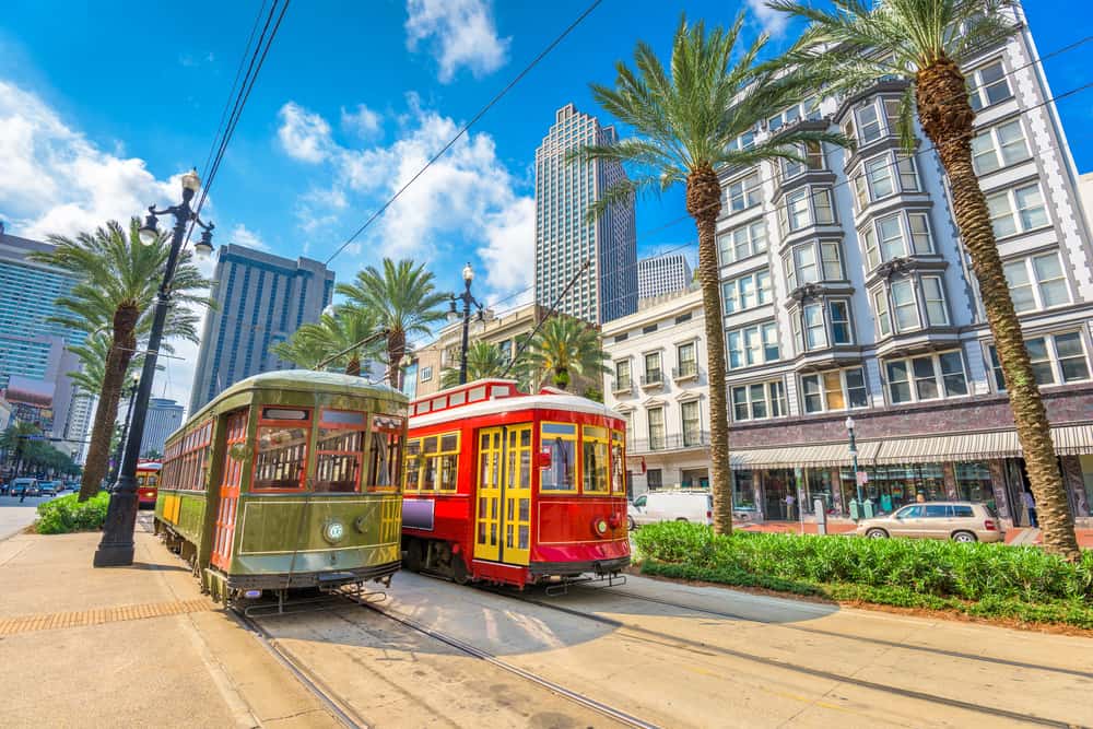 Two colorful streetcars drive through downtown New Orleans.