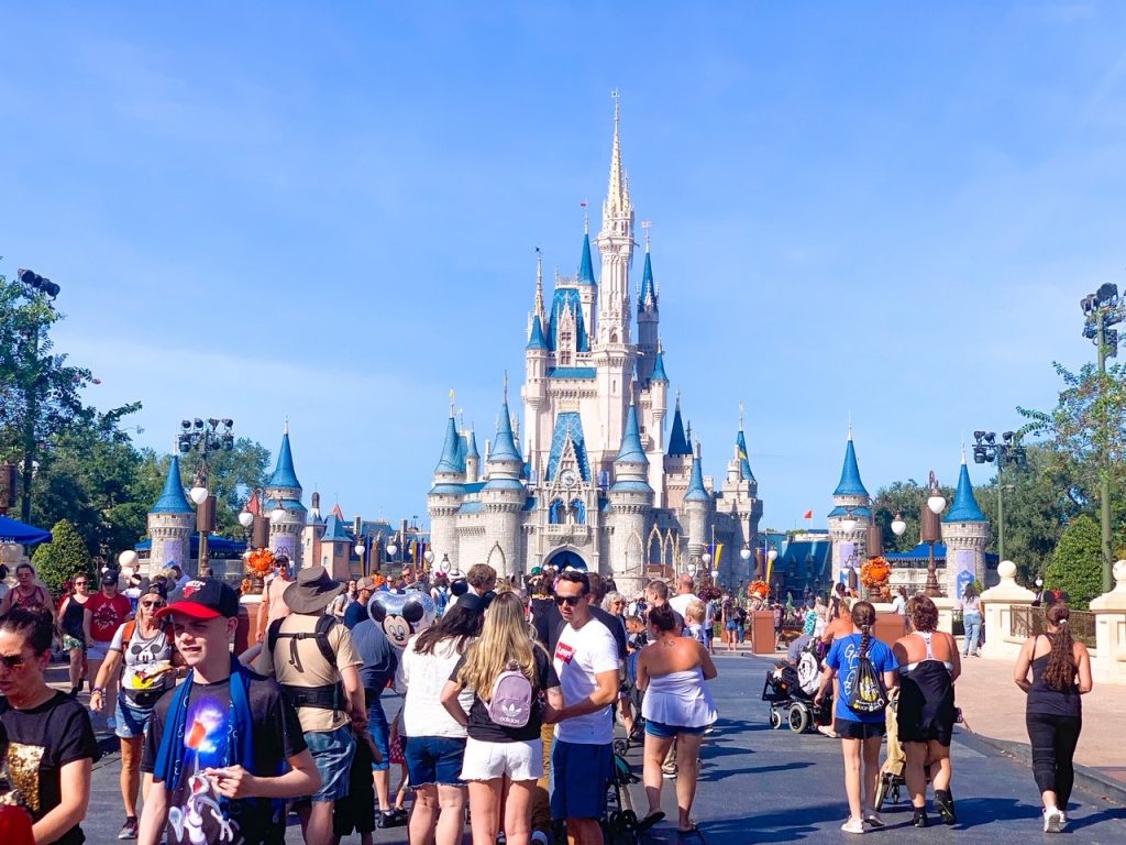 Photo of the iconic Cinderella Castle with its blue roofs in a crowd of people. 