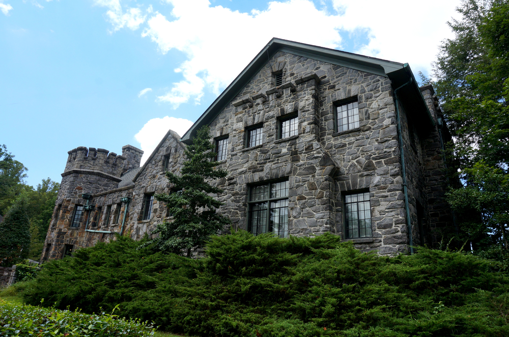 Photo of the gray stony exterior of Homewood with contrasting vibrant green shrubbery. 