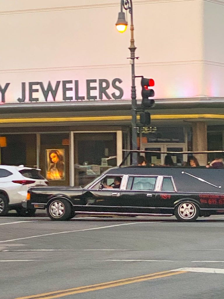 A hearse driving down the street with advertising on the side for ghost tours.