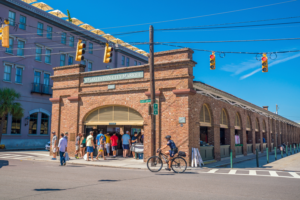 Exterior of the brick, Historic Charleston City Market with people going inside.