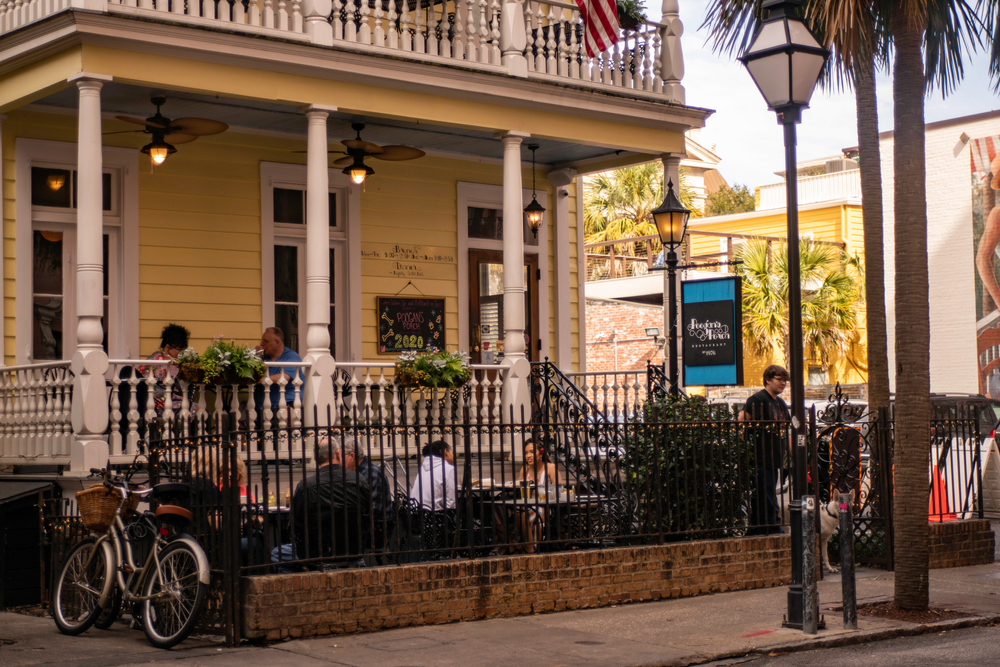 Exterior of yellow Poogan's Porch with people dining outside.