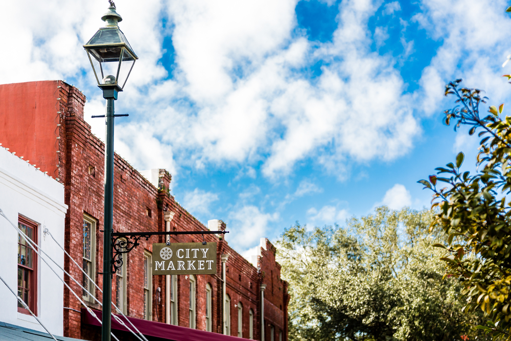 A old sign saying city market on a lamppost with building in the background. City Market is a great place for shopping in Savannah