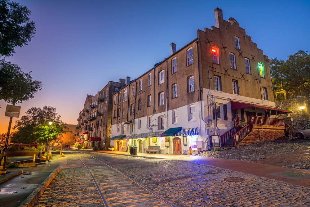 A street at night lit by lamps. River Street is a great place for shopping in Savannah