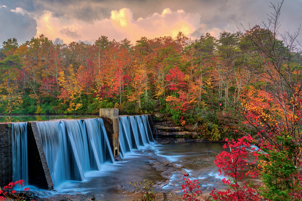 Bright reds and oranges of autumn leaves surround the peaceful and wide DeSoto Falls. 
